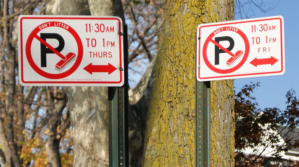 A pair of no-parking-during-street-sweeping-time signs.
