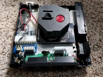 The insides of my modded Dreamcast.  The replacement power supply (Pico PSU) is visible on the left.  The black board in the middle is the GDEMU drive replacement, and the 3D printed bracket and insert sits atop that.